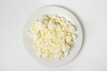 A plate of cottage cheese on a white background. Healthy and tasty dairy product.