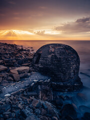 Vertical shot of a stone made bunker on the Azkorri Beach during sunset