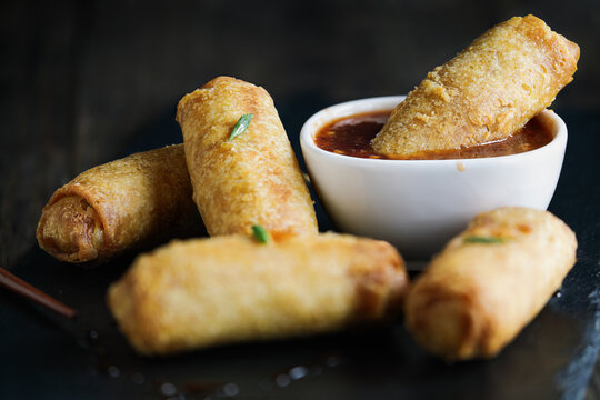 Fresh stack of egg rolls. Top eggroll is broken open to see the ingredients inside. Selective focus with blurred foreground and background. 
