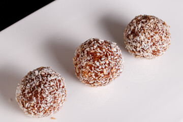 Beautiful sweets with coconut on a white plate on a black background