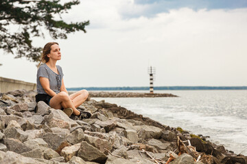 Beautiful girl on the sea overlooking the lighthouse and blue sky with clouds