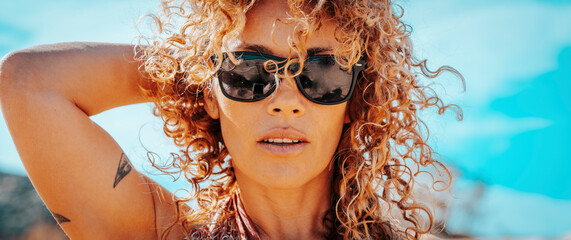 Summer portrait of beautiful young adult woman with sunglasses and healthy blonde long curly hair...