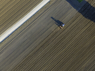 Aerial view of a tractor working in an agricultural field at sunset in Udine, Friuli Venezia Giulia
