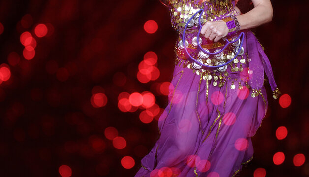 Belly dencer wearing purple dance costume and bokeh lights in the foreground