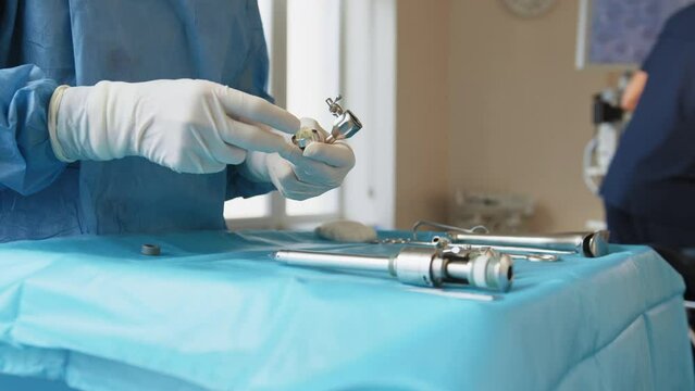 A table of medical tools are placed upon a table in preparation for robotic surgery. Surgical tools kit. Concept surgery. The surgeon's hands prepare the instrument for the operation.