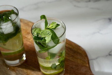 Non-alcoholic mojito with ice, mint and lime slices on wooden board. Refreshing summer cocktail.
