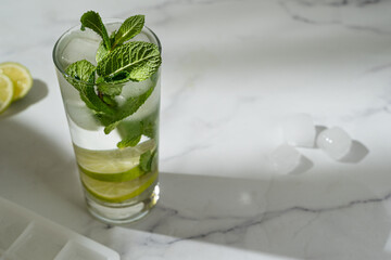 Non-alcoholic mojito with ice, mint and lime slices on the marble background. Refreshing summer cocktail.