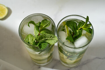 Non-alcoholic mojitos with ice, mint and lime slices on the marble background. Refreshing summer cocktails.