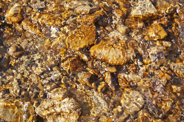 Clear water in a mountain river at the bottom of which lies the stones on a sunny day