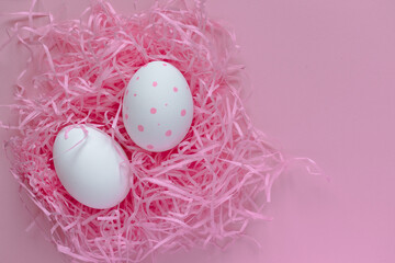 Easter layout. White painted eggs in a pink nest on a pink background. Bright Easter. Celebration. Postcard.