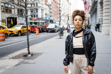 New York City lifestyle featuring young woman with curly hair wearing black leather jacket outside