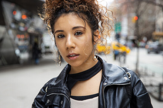 New York City lifestyle featuring young woman with curly hair wearing black leather jacket outside