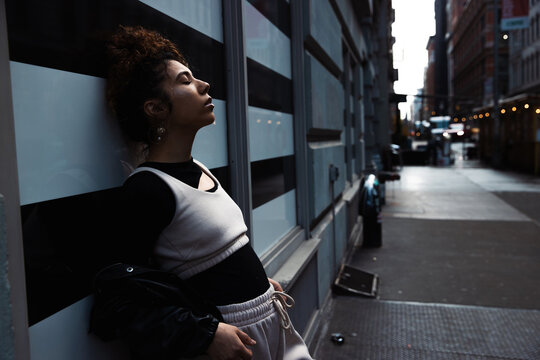 Dramatic light on young, mixed race woman with curly hair with eyes closed