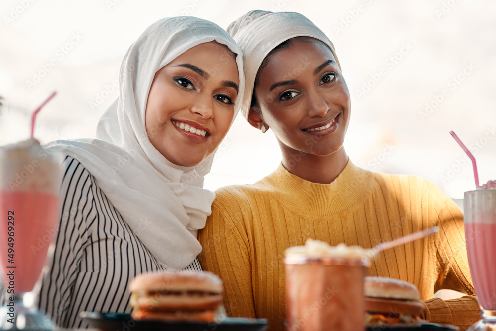 Canvas Prints This is where youll find us on weekends. Cropped portrait of two affectionate young girlfriends having a meal together at a cafe while dressed in hijab.