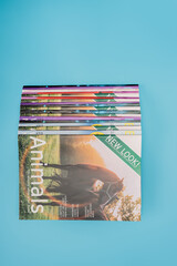 top view of colorful naturalistic magazines isolated on blue with copy space.