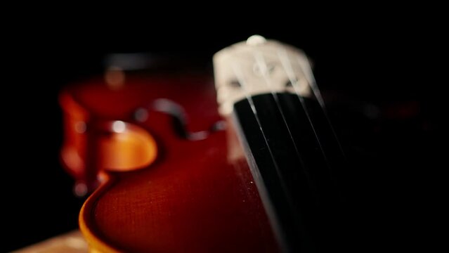 Classic violin musical instrument lies under the light in a dark studio, close-up.