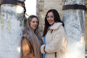 lesbian couple leaning on columns surrounding the gothic style cathedral. The women look at each other in love and happy. Concept of homosexual and lesbian marriage.