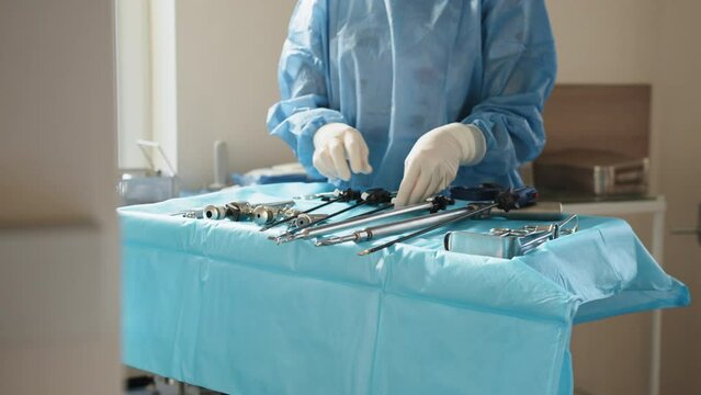 Surgical instrument. Preparation for surgery. Close laparoscopic instruments. Use of laparoscopic equipment. Portrait of female medical worker in protective mask preparing for surgery.