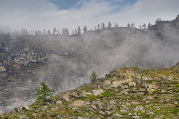 Russia. South of Western Siberia, Mountain Altai. Morning frosty fog on the tops of the rocks along...