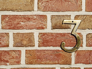 Closeup of a metal number on a brick wall