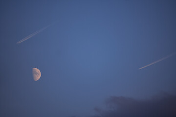 Beautiful view of an airplane contrail and the moon