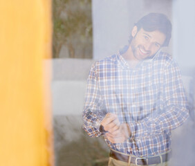 The days off to a great start. Through the glass shot of a handsome man getting dressed while talking on the phone.