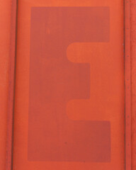 Close up of a red letter E on a red background.