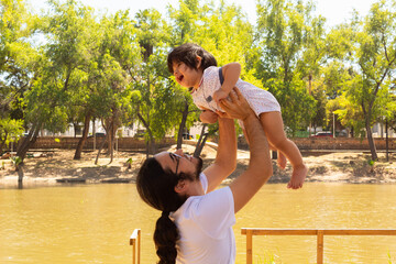portrait of a Hispanic father and baby in a park smiling and having fun