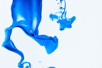 Blue paint splash curves in water on white. Acrylic paint drop background. Abstract color swirl texture