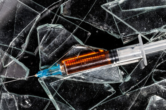 medical syringe with drug close-up on broken glass