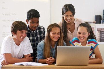 Using all the resources the internet has to offer. Shot of a group of schoolchildren using a laptop in class with their teacher.