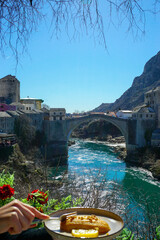  traditional  dessert called hurmasica with beautiful  view on  Old Bridge, Mostar