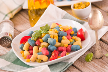 Colored gnocchi with vegetables and sweet corn.