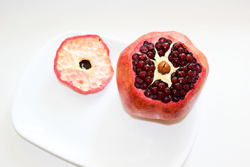 Cut ripe pomegranate into pieces on a white background