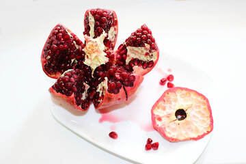 Cut ripe pomegranate into pieces on a white background