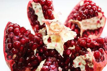 Cut ripe pomegranate into pieces on a white background