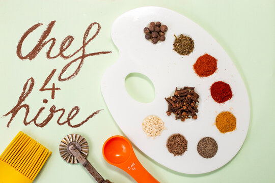 Chef 4 hire written on paper next to a painter's palette with dried spices, and kitchen tools