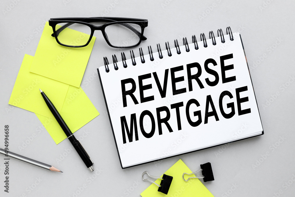 Poster reverse mortgage stickers and notepad on a gray background. text on notebook.