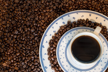 Black traditionl coffee cup on many coffee beans at background 