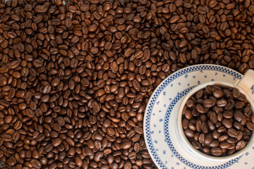 Many coffee beans in a traditional cup and at background 