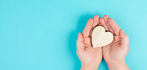 Woman is holding a red heart in her hand, blue colored background, copy space, love and charity symbol, hope concept

