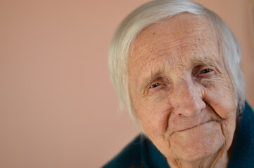 Portrait of a smiling senior 90 years woman. Studio shot over beige background.