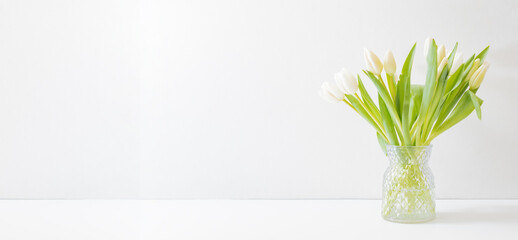White spring tulips in a vase on a white table. Mock up for displaying works