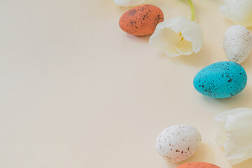Easter composition with white tulips and easter eggs on a beige background