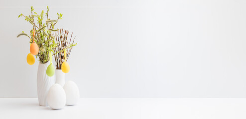 Willow branches in a vase and easter eggs on a light background. Easter background with copy space
