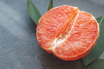 Half a fresh, juicy grapefruit on a dark marble background