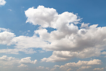 Obraz premium White clouds float across the blue sky over the yellow steppe land