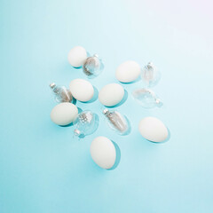 A pile of white eggs and transparent egg shells with grey feathers