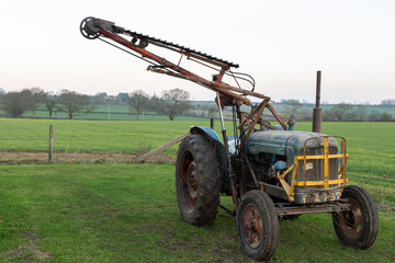 An antique cutter bar hedge trimmer mounted on a vintage tractor