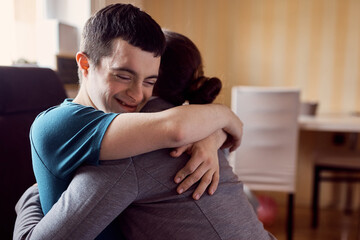 Happy man with down syndrome hugs his therapist during home visit.